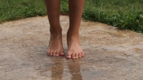 Kid joyfully jumping in rainwater puddle in the backyard on a rainy day Stockbeeldmateriaal 287376462