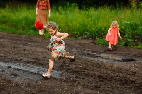Kid jumping through puddle road after rain Foto stock