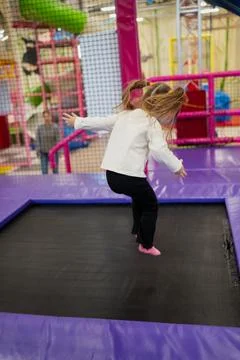 Kid jumping on a trampoline inside a fun indoor play park featuring soft pads Stock Photos