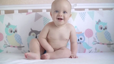 Kid learn to sit in the crib and smiles at the camera. Joyful baby. Slow Stock Footage 80325378