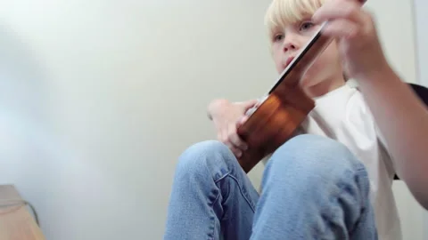 Kid is learning how to play ukulele using computer program. Video stock 223799760