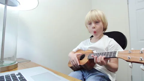 Kid is learning how to play ukulele using computer program. Stock Footage 223799769
