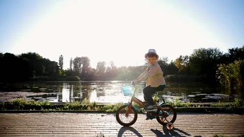 Kid is learning to ride bike. Child rides bicycle on rural road Stock Footage 269444301