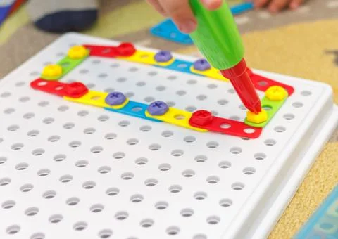 Kid learning to use screwdriver. Multicolor screws. Future occupation concept Stock Photos