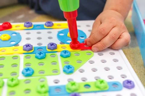 Kid learning to use screwdriver. Multicolor screws. Future occupation concept Stock Photos