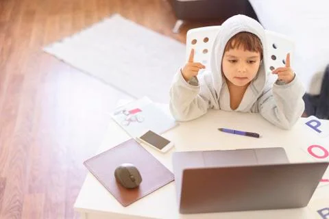 Kid learns at the computer on-line. Child boy learning letters and alphabet at Stock Photos