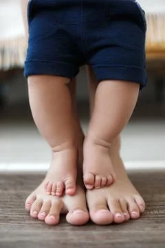 The kid learns to take first steps with the help of his mother Stock Photos