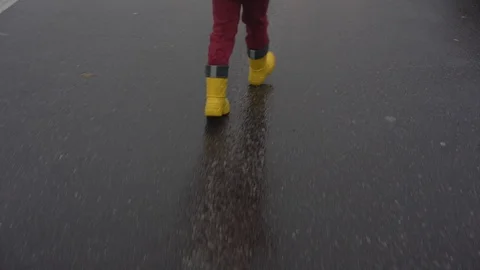 Kid legs in red pants and yellow waterproof rubber boots Stock Footage 122245210