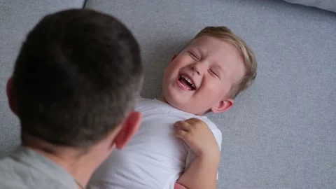 The kid lies on the couch and laughs while playing with dad. Stock Footage 150590584