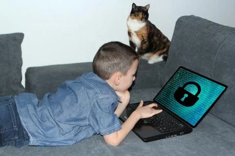 Kid lies on the couch in front of an open laptop, lock symbol appears on the  Foto stock