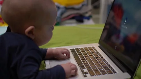 Kid lies in front of computer and types a passward. Handheld shot Stock Footage 72632490