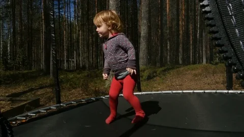 Kid, little girl, jump on trampoline in park at summer day Stock Footage