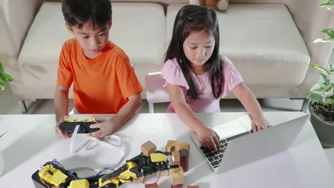 Kid little girl program code to robot with laptop computer and the boy test with Stock Footage 192284589