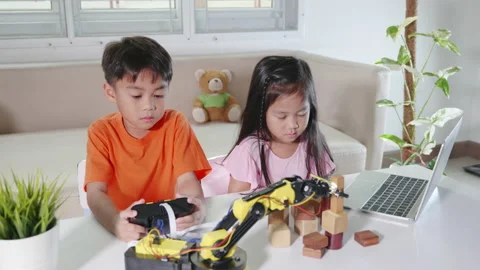 Kid little girl program code to robot with laptop computer and boy test remote Stock Footage 224409242