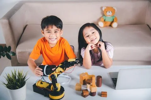 Kid little girl program code to robot with laptop computer and the boy test w Stock Photos