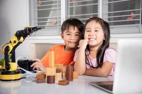 Kid little girl program code to robot with laptop computer and the boy test with Stock Photos