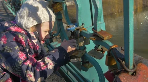 Kid is Looking at the Padlocks Locked on a Bridge Metal Rods Symbol of Eternal Stock Footage 60436475