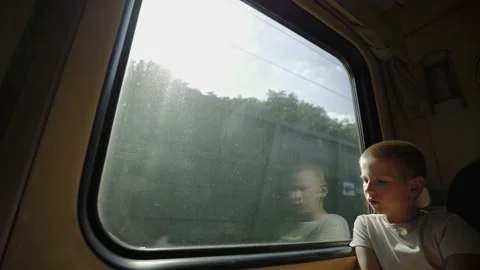 Kid looks out the train window. Boy is traveling by train. Oncoming train. Stock Footage 148168021