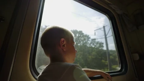 Kid looks out the train window. Thoughtful boy in a train compartment. Stockbeeldmateriaal 149240793