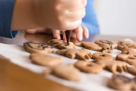 Kid making decoration on gingerbread cookie close up. Baking with children Stock Photos