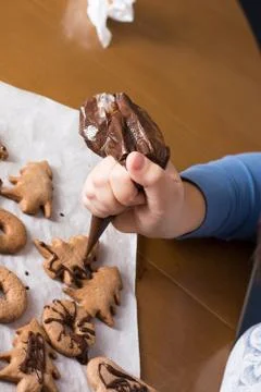 Kid making decoration on gingerbread cookie close up. Baking with children Stock Photos