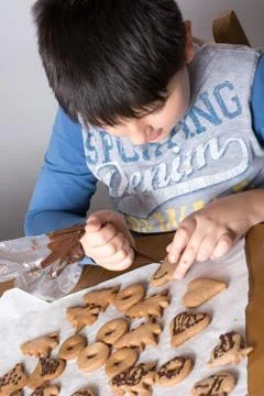Kid making decoration on gingerbread cookie close up. Baking with children Stock Photos