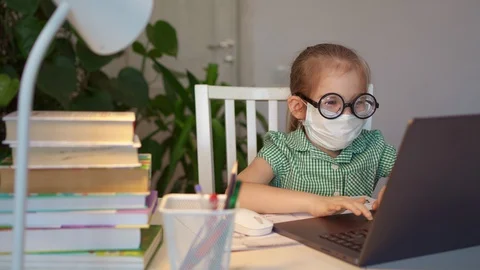 Kid in mask with glasses learn remote on laptop Stock Footage 129758261