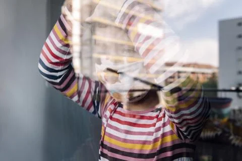 Kid with mask looking through the window Stock Photos