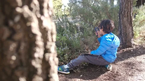 Kid naturalist seated down explores the life of plants and insects Stock Footage 238369141