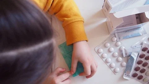 Kid opens Organizer with white and brown pills, takes to go Close up above Stock Footage 128570713