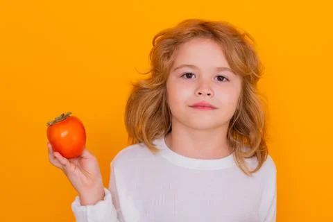 Kid with persimmon in studio. Studio portrait of cute child hold persimmon Fotos Stock