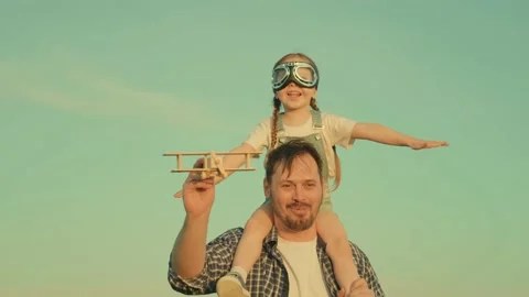Kid, pilot sits on his dads shoulders in pilots goggles. Teamwork father, child Video stock 189569558