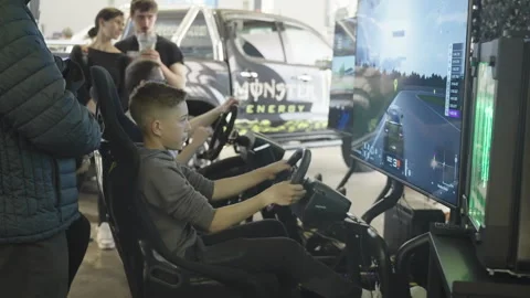 Kid play racing simulation on big television at Auto Motor Show Ljubljana 4K Stock Footage 309780648