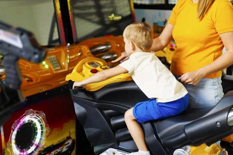 Kid playing arcade simulator machine at an amusement park. Stock Photos