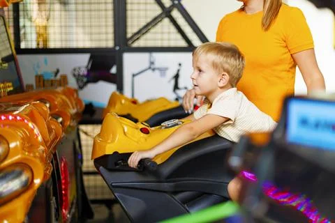 Kid playing arcade simulator machine at an amusement park. Stock Photos