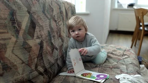 Kid playing with a book at home Stock Footage 147660437