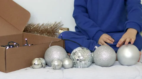 Kid playing with christmas tree balls inside home Stock Footage 223511169