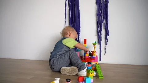 Kid playing with colored blocks of constructor on wooden floor. Gimbal motion Stock Footage 114899421