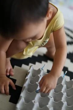 A kid playing with an egg tray to develop his sensory skills Stock Photos