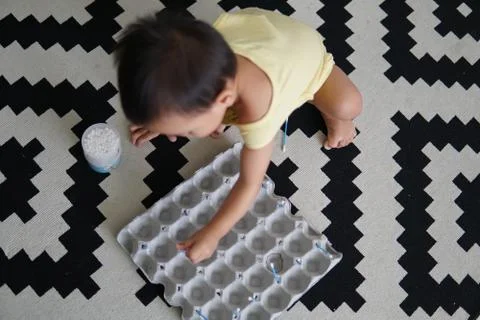 A kid playing with an egg tray to develop his sensory skills Stock Photos