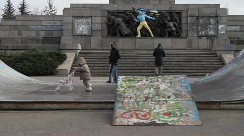 Kid playing in front of a Soviet monument in Sofia painted in colours of Ukraine Stock Footage 35527680