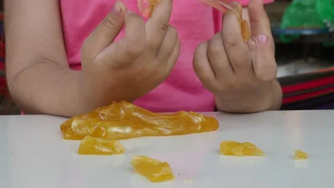 Kid Playing Hand Made Toy Called Slime. cute girl plays with a yellow slime 動画素材 167314807
