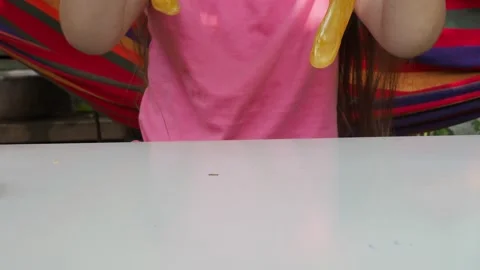 Kid Playing Hand Made Toy Called Slime. cute girl plays with a yellow slime 動画素材 167314949