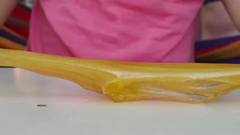 Kid Playing Hand Made Toy Called Slime. cute girl plays with a yellow slime 動画素材 167314972