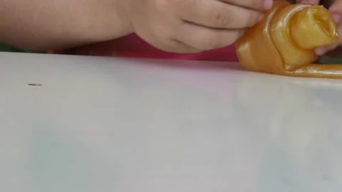 Kid Playing Hand Made Toy Called Slime. cute girl plays with a yellow slime 動画素材 167315201