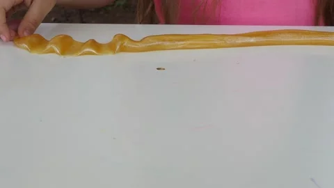 Kid Playing Hand Made Toy Called Slime. cute girl plays with a yellow slime 動画素材 167315203