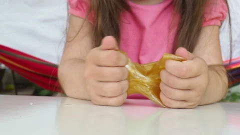 Kid Playing Hand Made Toy Called Slime. cute girl plays with a yellow slime 動画素材 167315207