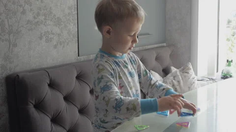 Kid playing with a magnetic constructor toy on a table at home Stock Footage 158686684