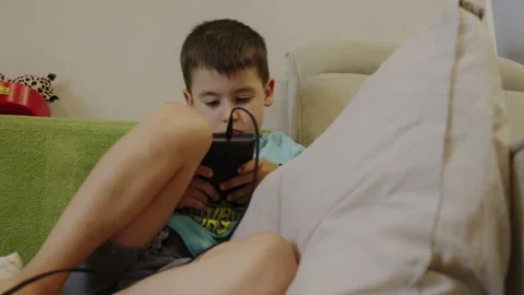 Kid playing portable online gamming console device by handheld in room. Child Stock Footage 252172630