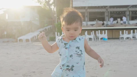 Kid playing on sand beach. Cute baby boy walks along seaside coast in summer.  Stock Footage 241393710